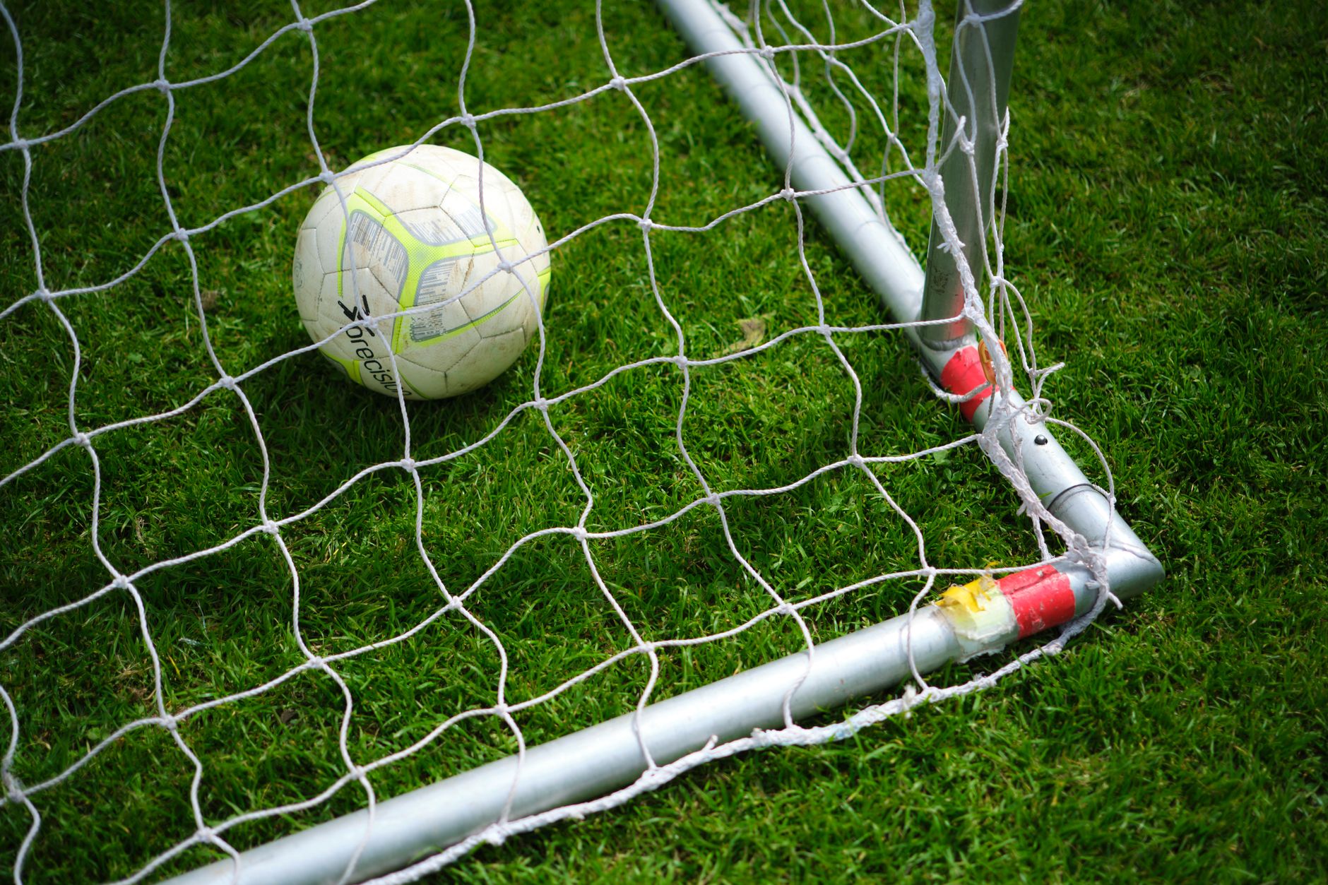 A soccer ball resting in the corner of a goal net