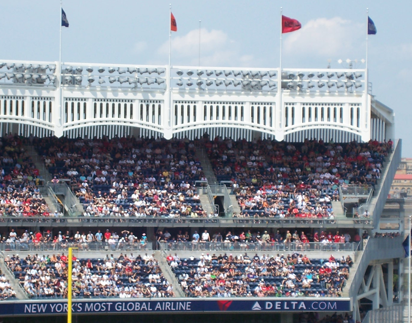The upper deck and facade of Yankee Stadium filled with fans during a game.