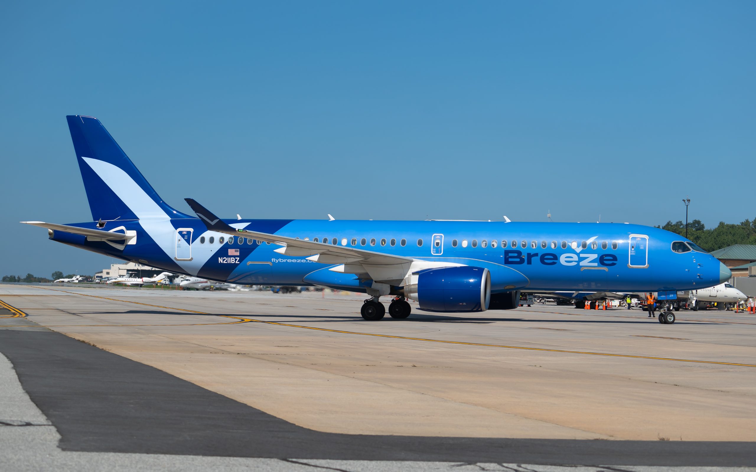 A Breeze Airways Airbus A220 aircraft with blue livery on the tarmac