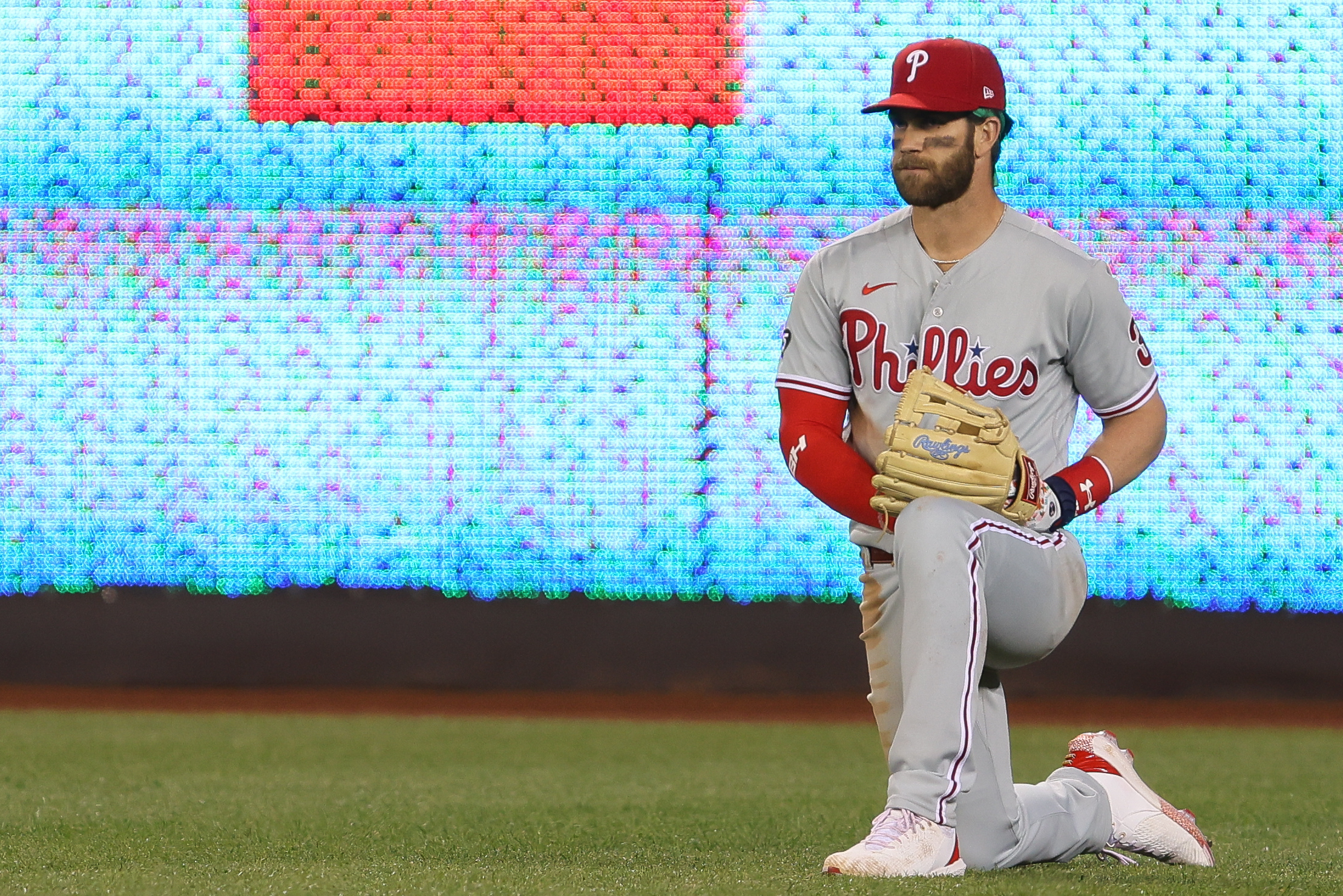 Bryce Harper kneeling on the field in a Phillies uniform