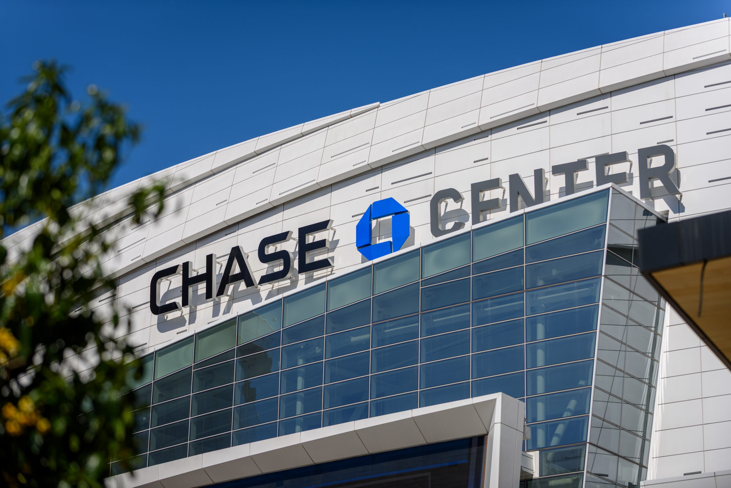 The Chase Center arena exterior in San Francisco, showing the venue's name and logo on its curved white facade.