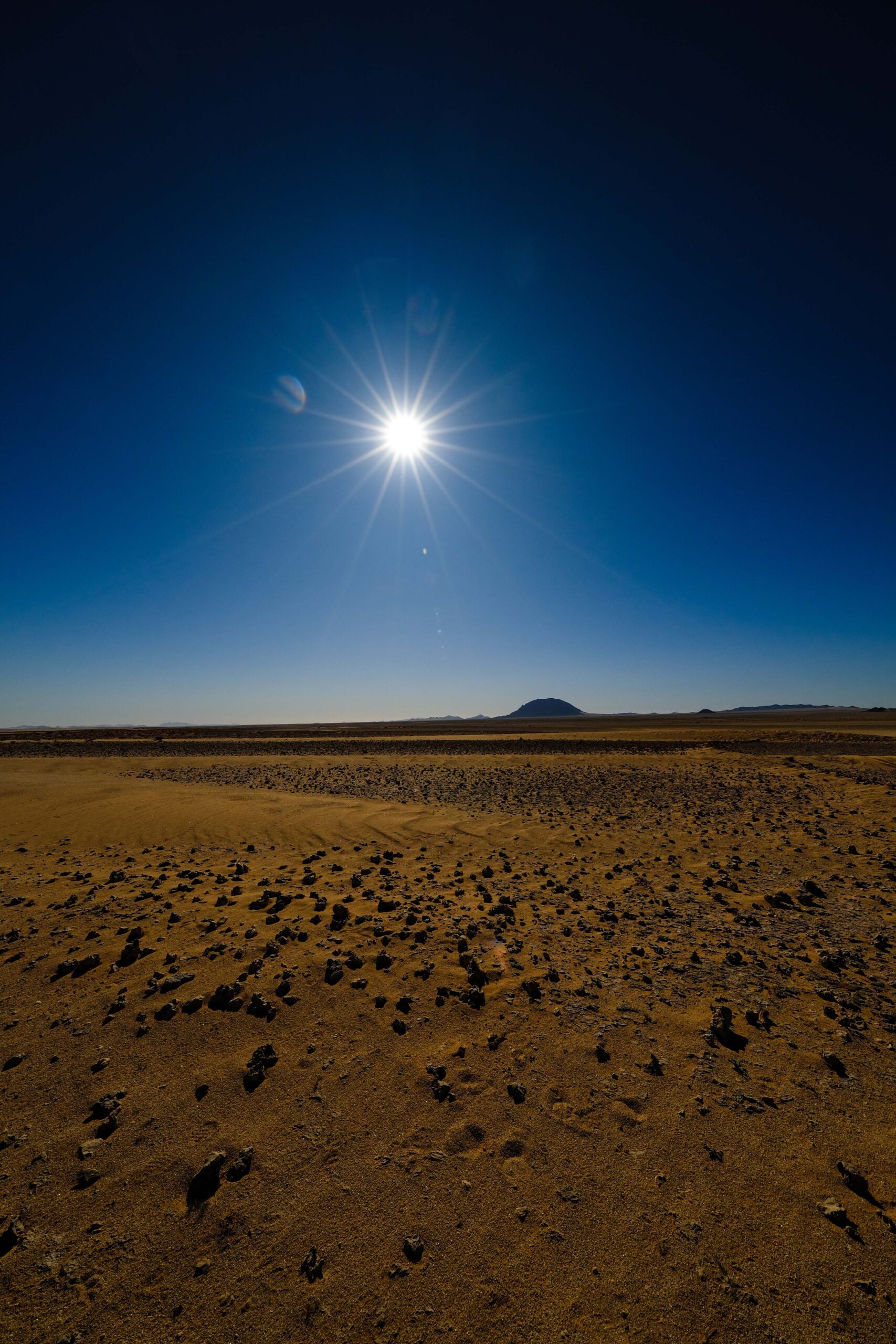 The sun blazing over a rocky desert landscape