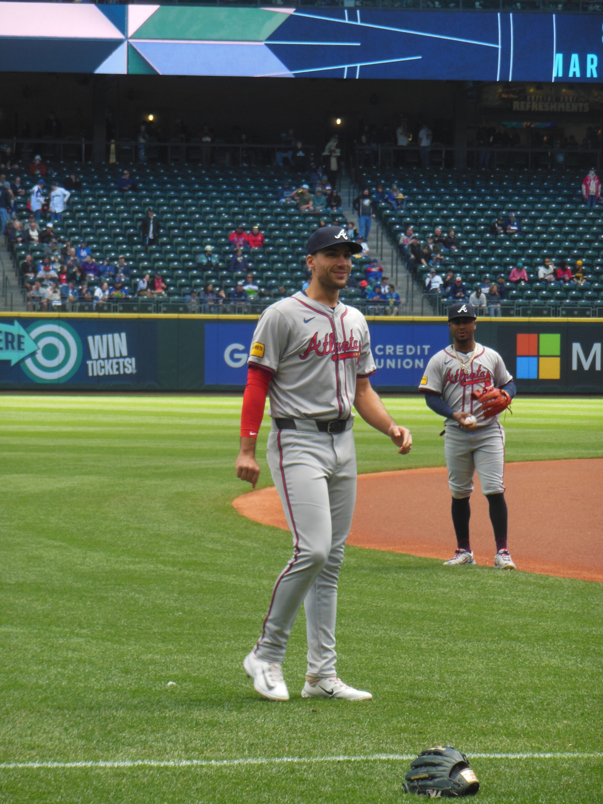 Atlanta Braves players Matt Olson and Ozzie Albies on the field in road uniforms during warmups.