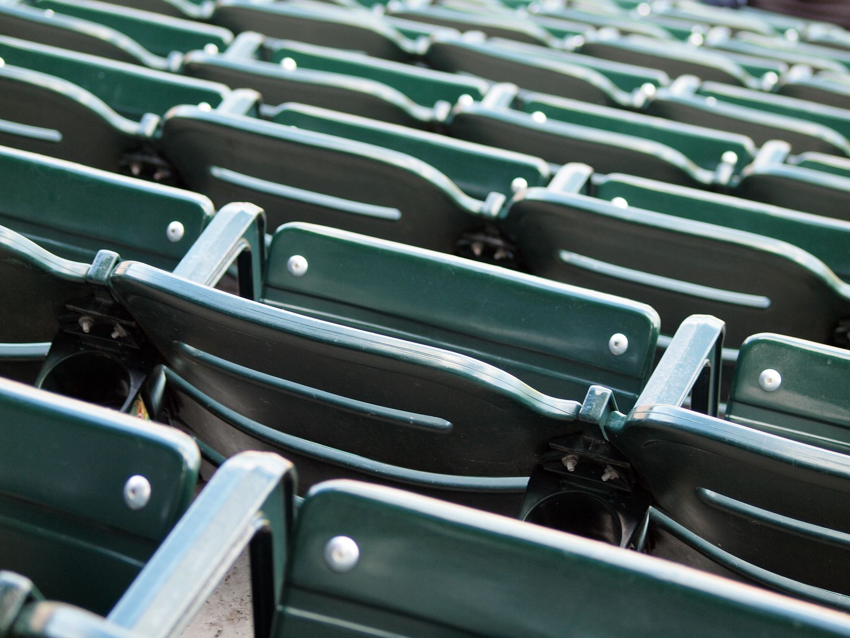 Photo: Close-up view of empty green stadium seats arranged in rows, conveying a sporting venue atmosphere.