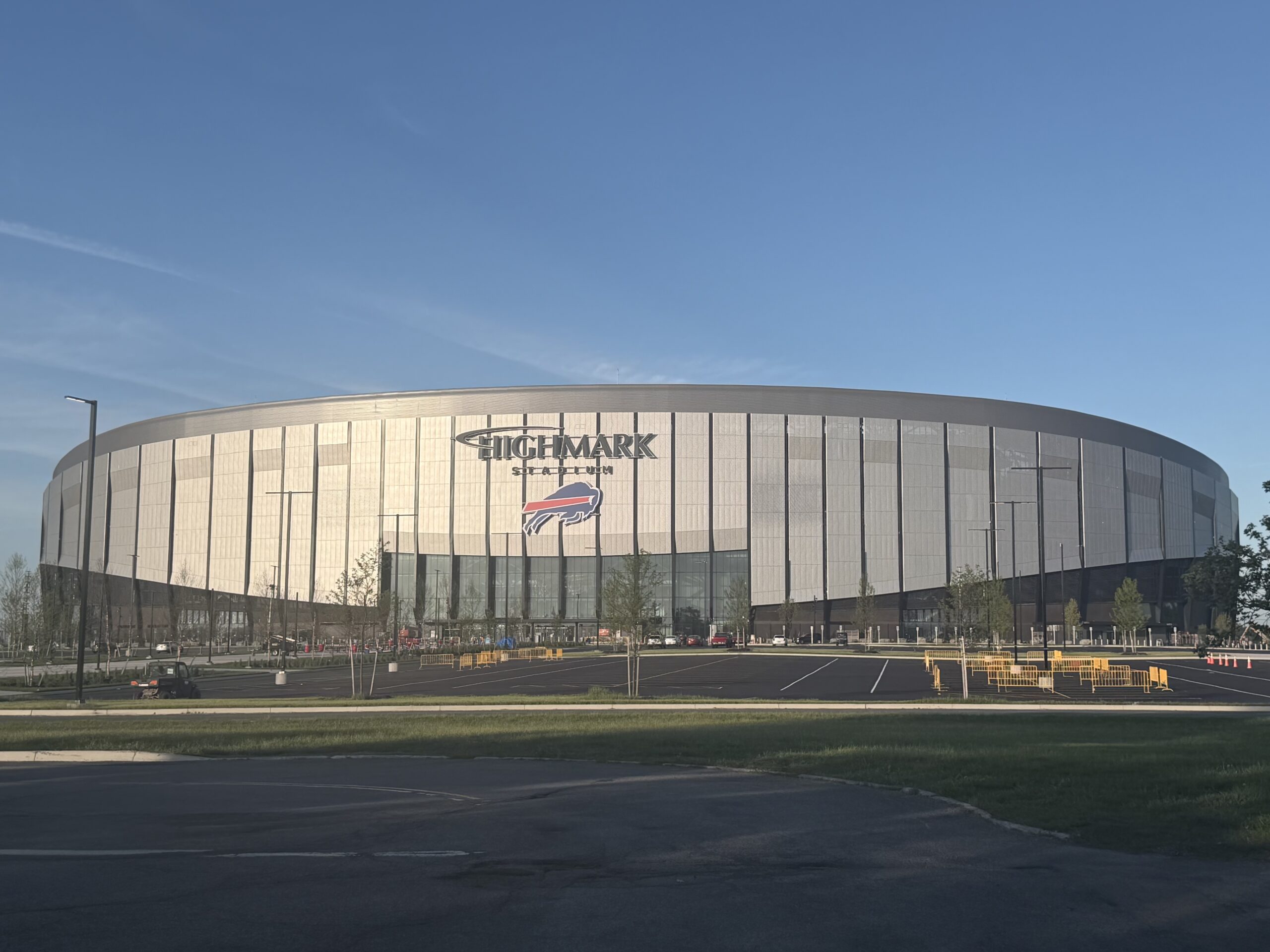 Exterior view of the new Highmark Stadium, an oval NFL stadium with a large HIGHMARK STADIUM sign and the Buffalo Bills logo above the main entrance.