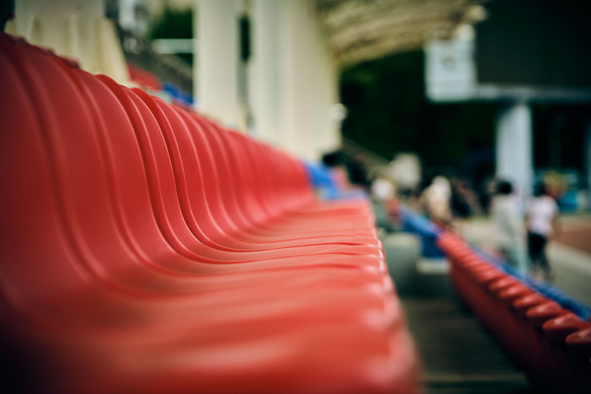 Photo: A close-up view of red plastic stadium seats with a blurred background.