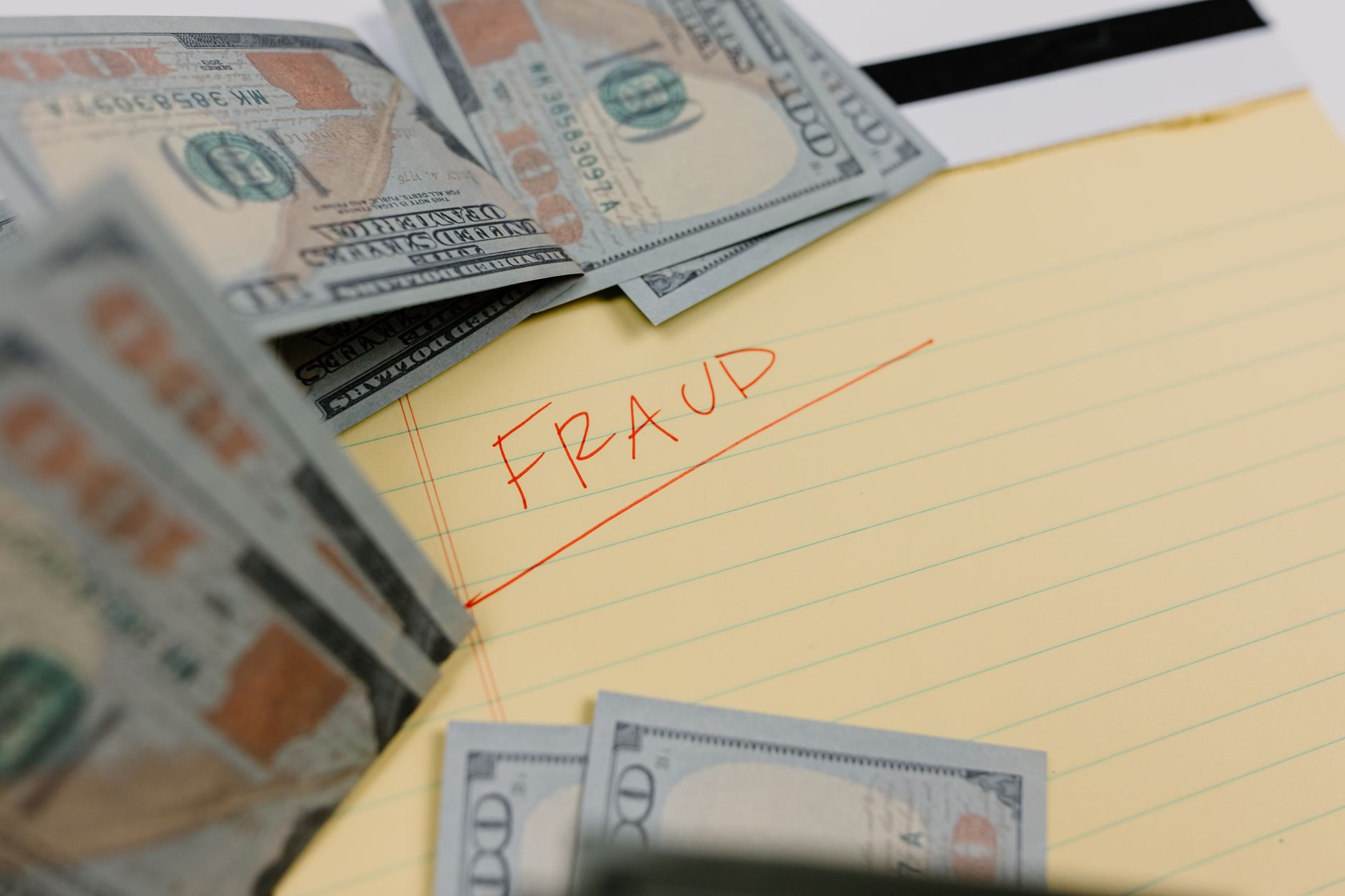 Cash and a handwritten note reading FRAUD on a legal pad