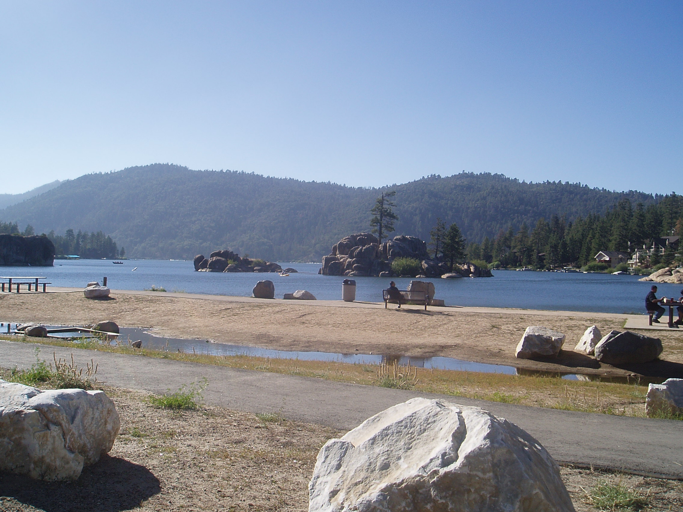 Big Bear Lake in California, seen from the shore, with pine-covered mountains behind it