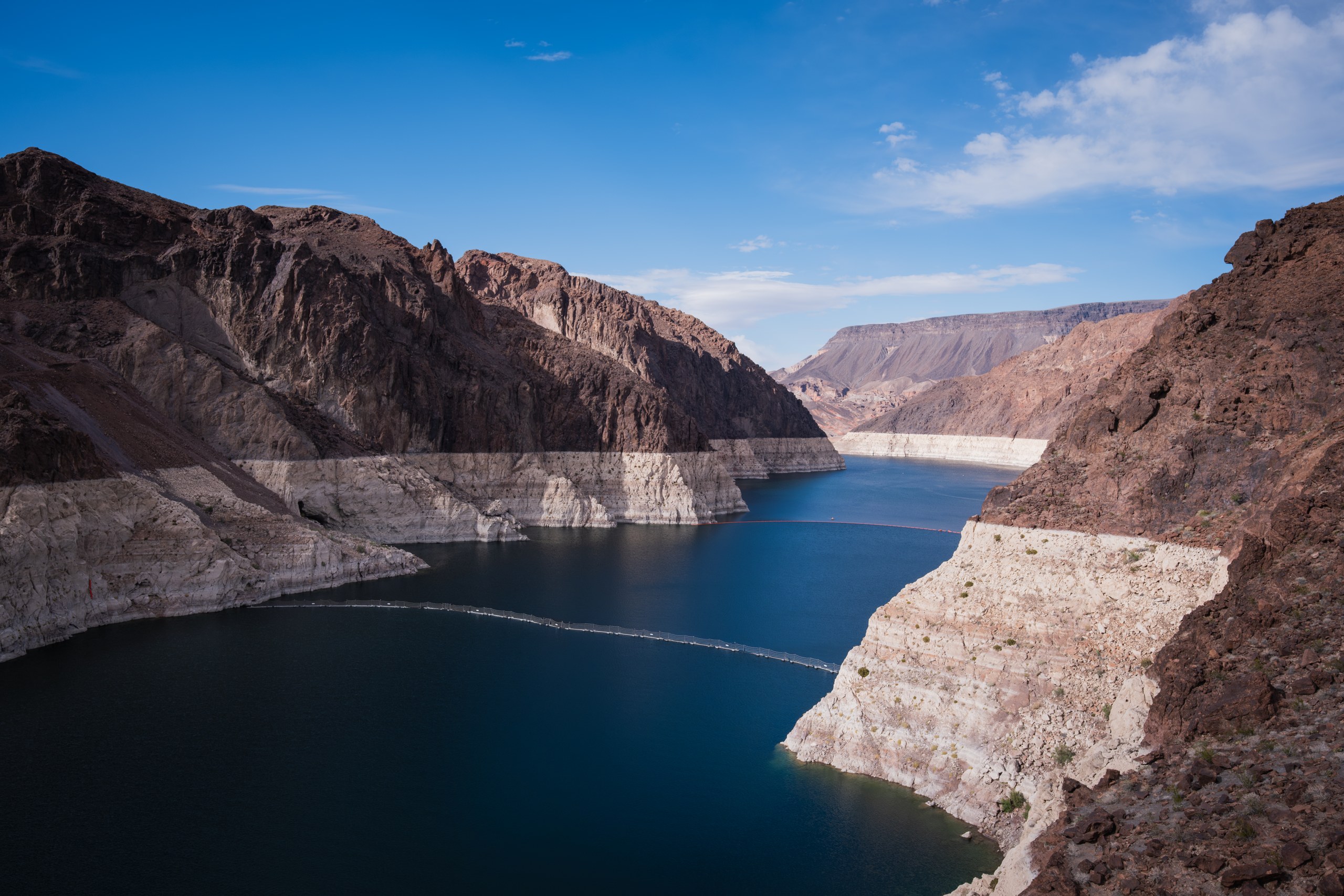 Lake Mead upstream of Hoover Dam in Black Canyon, with a wide white mineral band — the bathtub ring — marking how far the reservoir has dropped below its old shoreline.