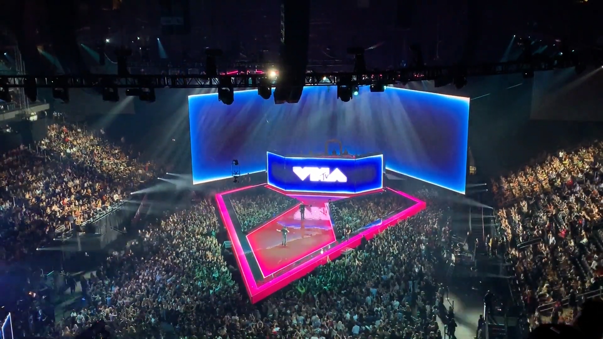 The MTV Video Music Awards main stage, lit blue and pink, packed with an arena crowd