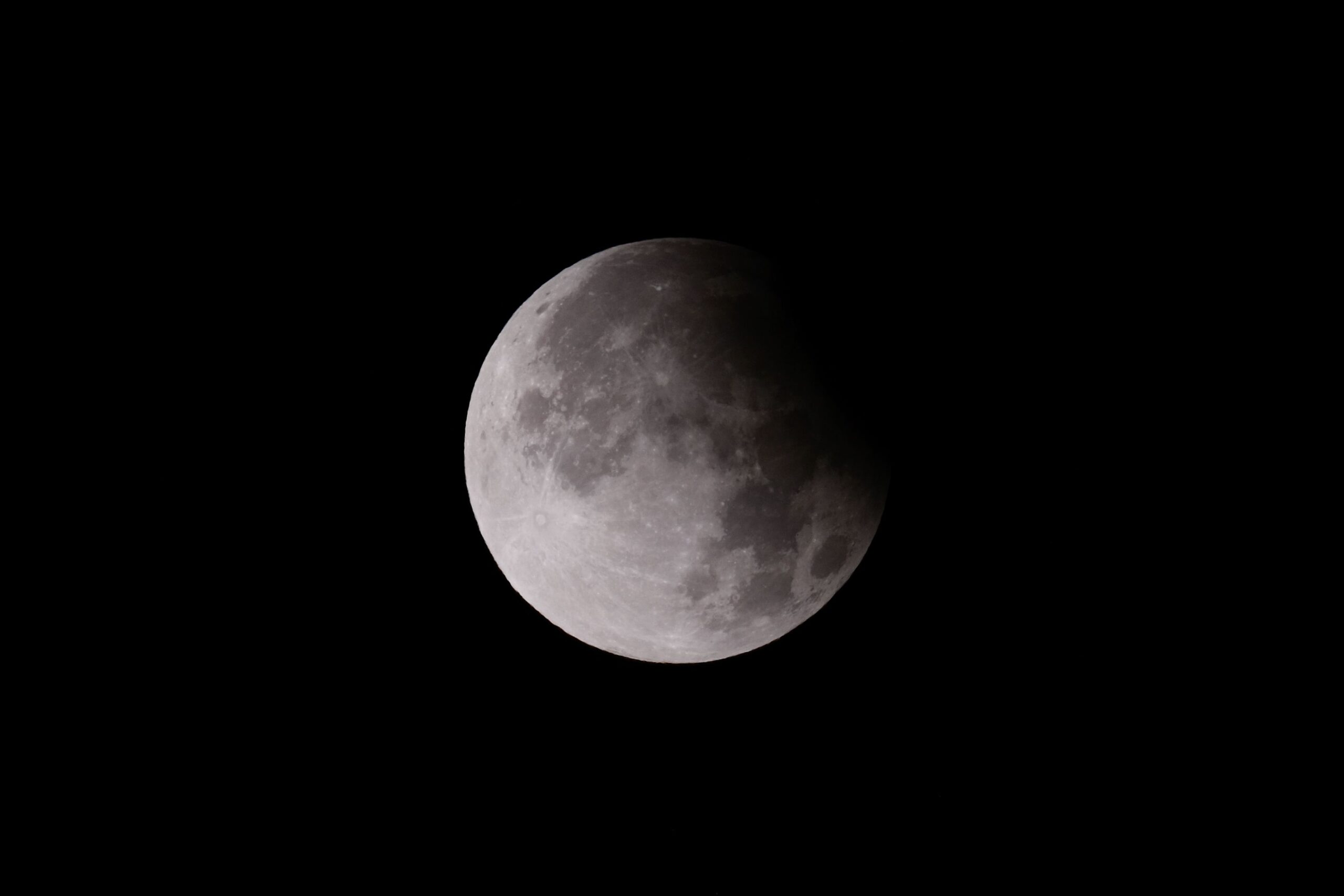 The Moon partway through a lunar eclipse, with Earth's shadow visibly darkening one edge