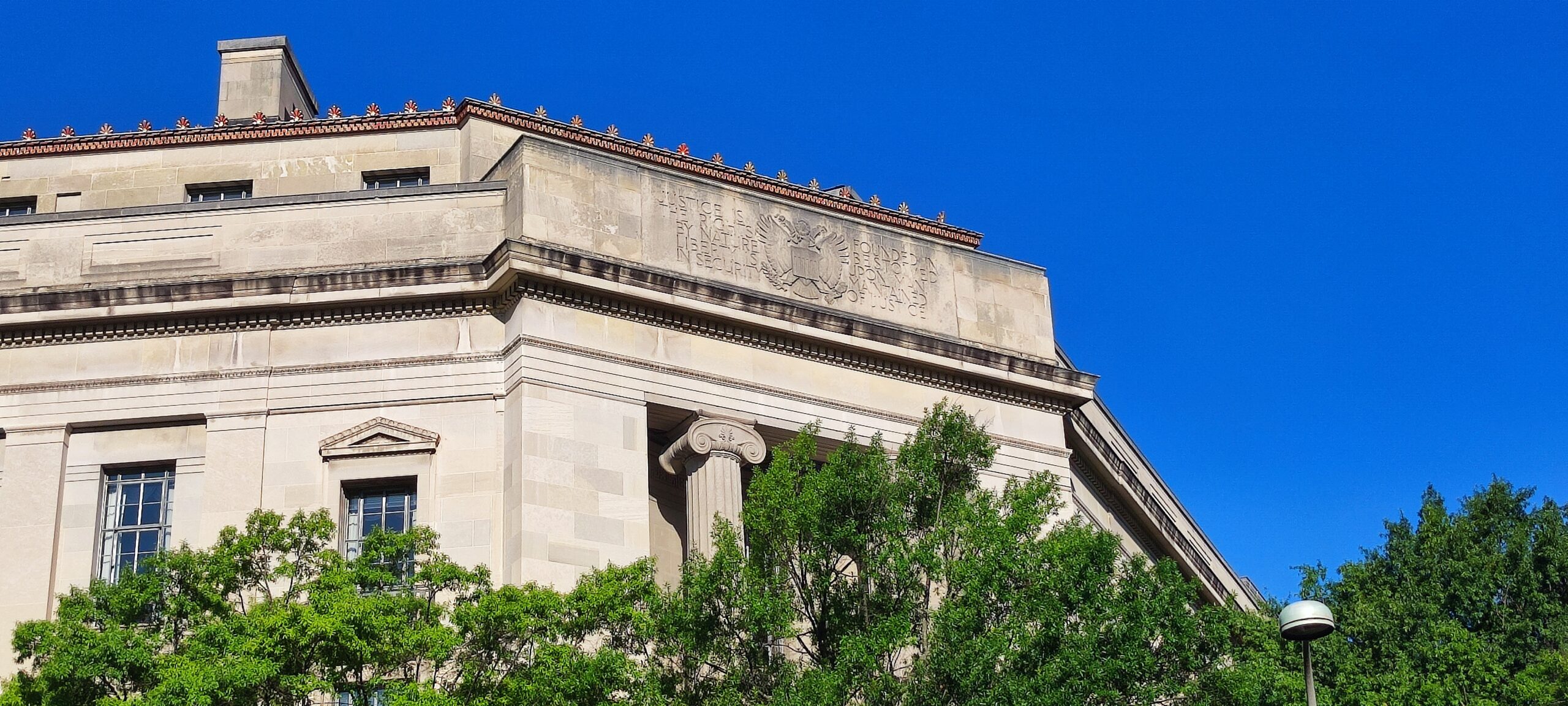 The Robert F. Kennedy Department of Justice Building in Washington, D.C., with its 'Justice is founded in liberty' inscription visible.