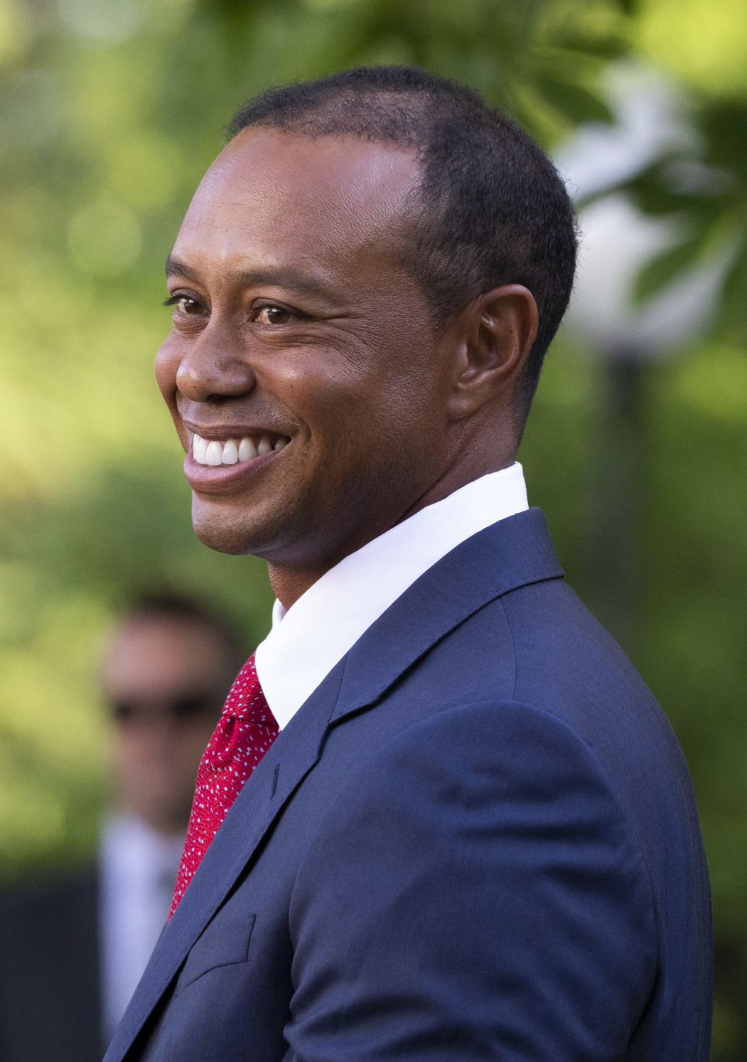 Tiger Woods smiling in a navy suit and red tie
