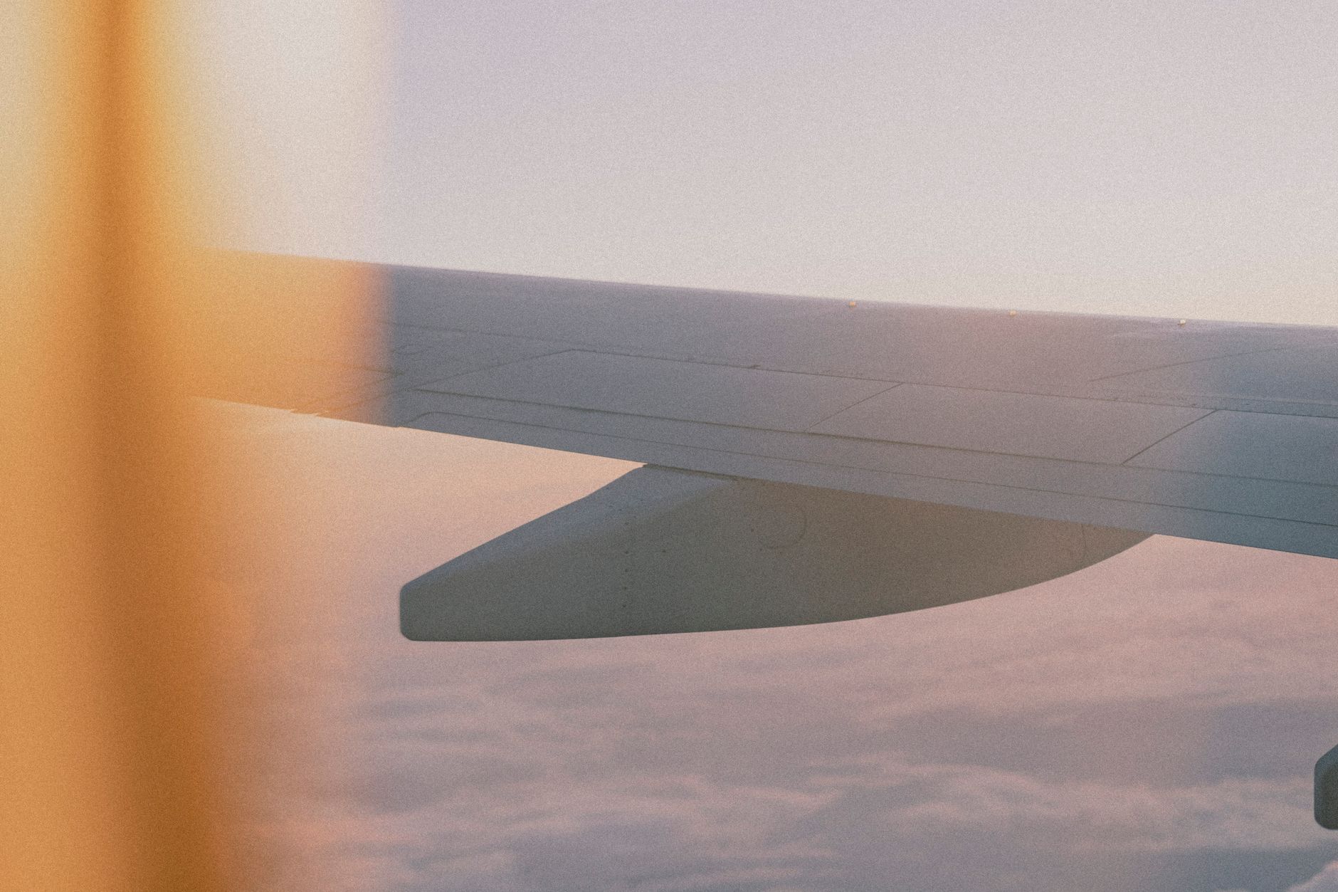 View of an airplane wing above the clouds from a window seat during flight.