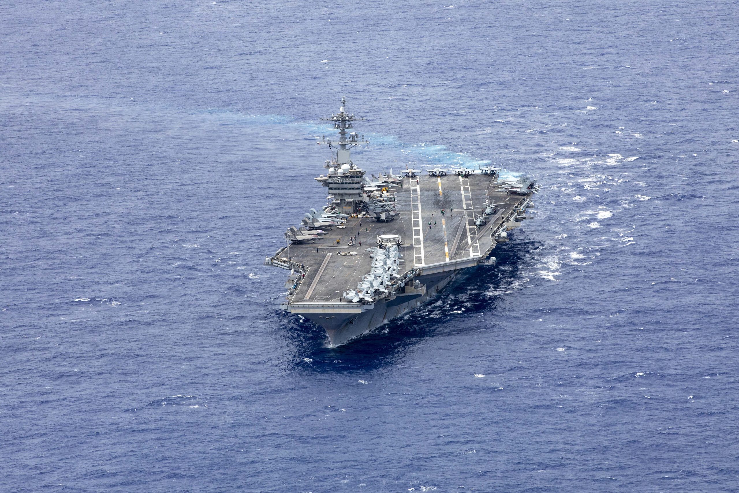 The aircraft carrier USS Abraham Lincoln (CVN-72) transits the open ocean with aircraft on its flight deck.