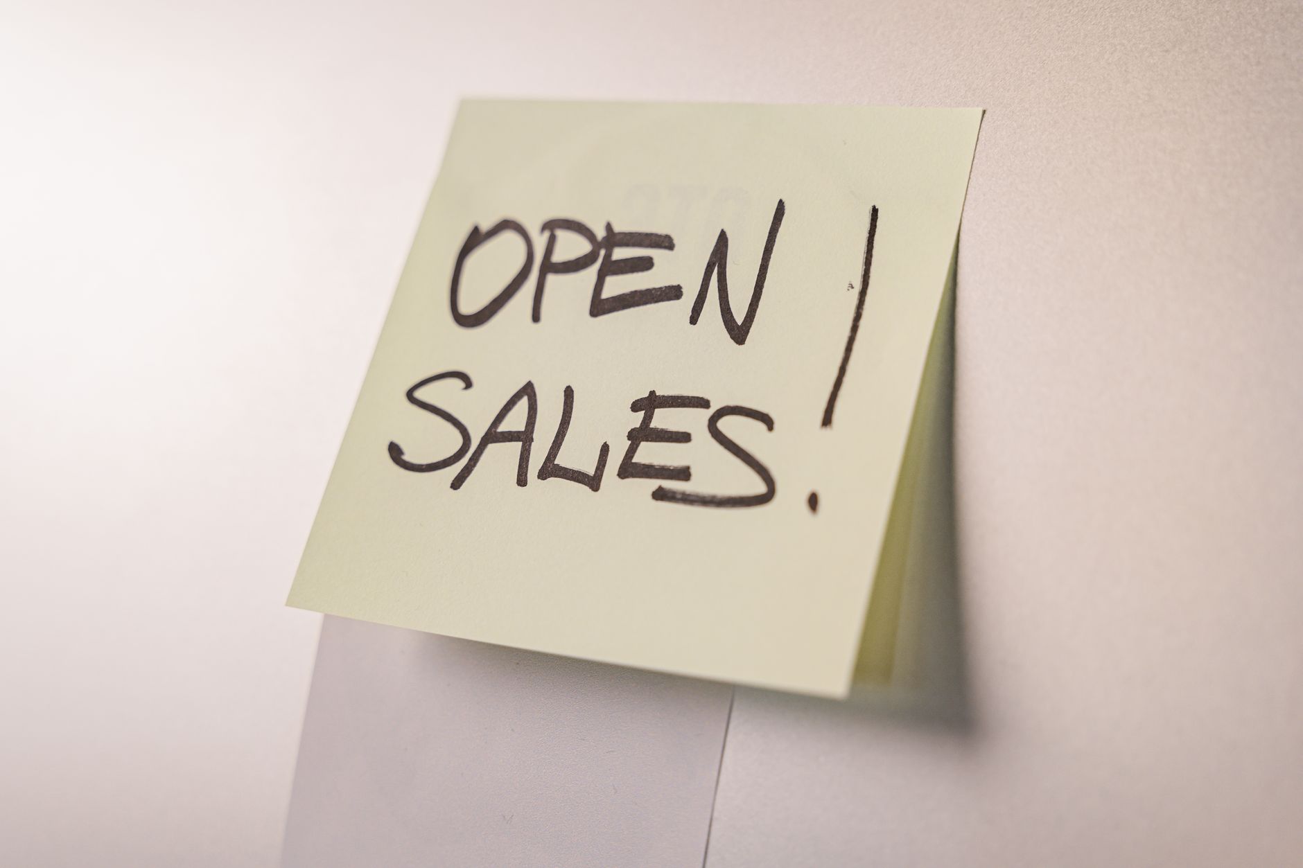 A sticky note reading "Open Sales!" on a wall
