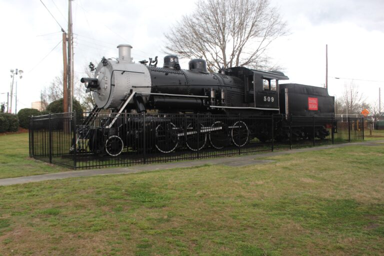 A black Central of Georgia steam locomotive, number 509, displayed behind an iron fence on a lawn in Carolyn Crayton Park in Macon, Georgia.