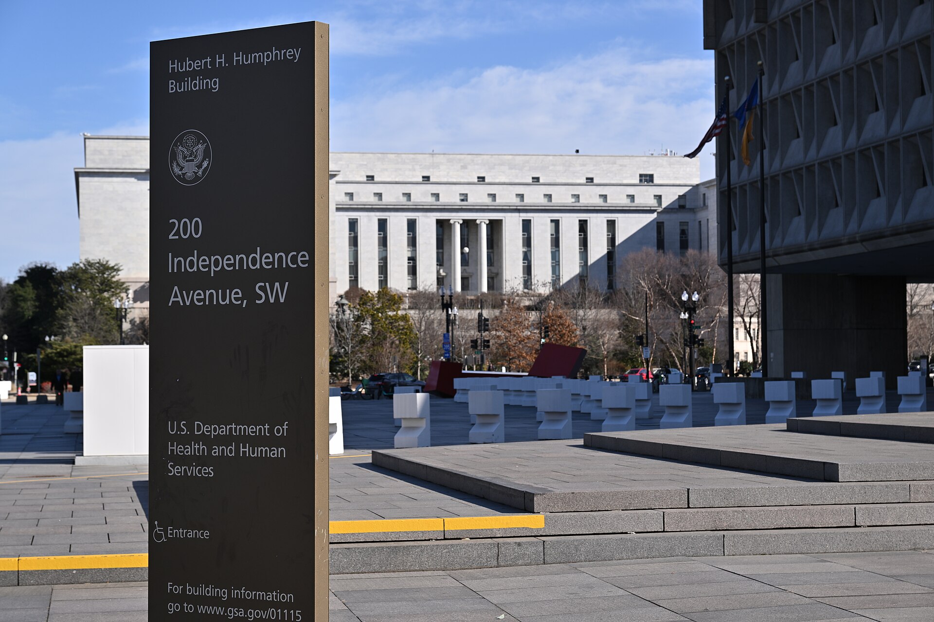 A dark sign reading Hubert H. Humphrey Building, 200 Independence Avenue SW, U.S. Department of Health and Human Services, outside the building in Washington, D.C.