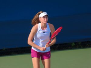Elena Rybakina, wearing a white visor and top, holds her racket during a match at the US Open.