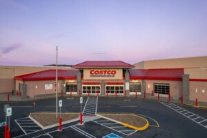 The entrance of a Costco Wholesale warehouse store in Fredericksburg, Virginia, with its red roof and an empty parking lot at dusk.