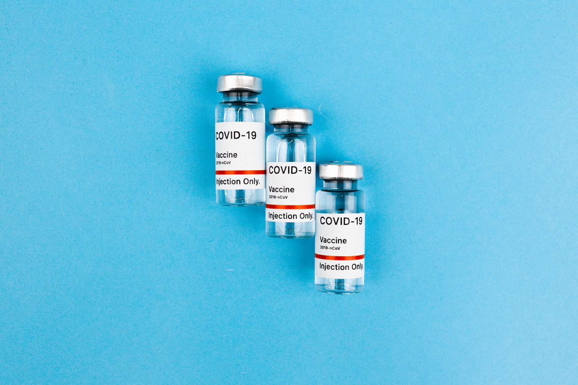 Three vials labeled COVID-19 Vaccine, injection only, on a blue background.