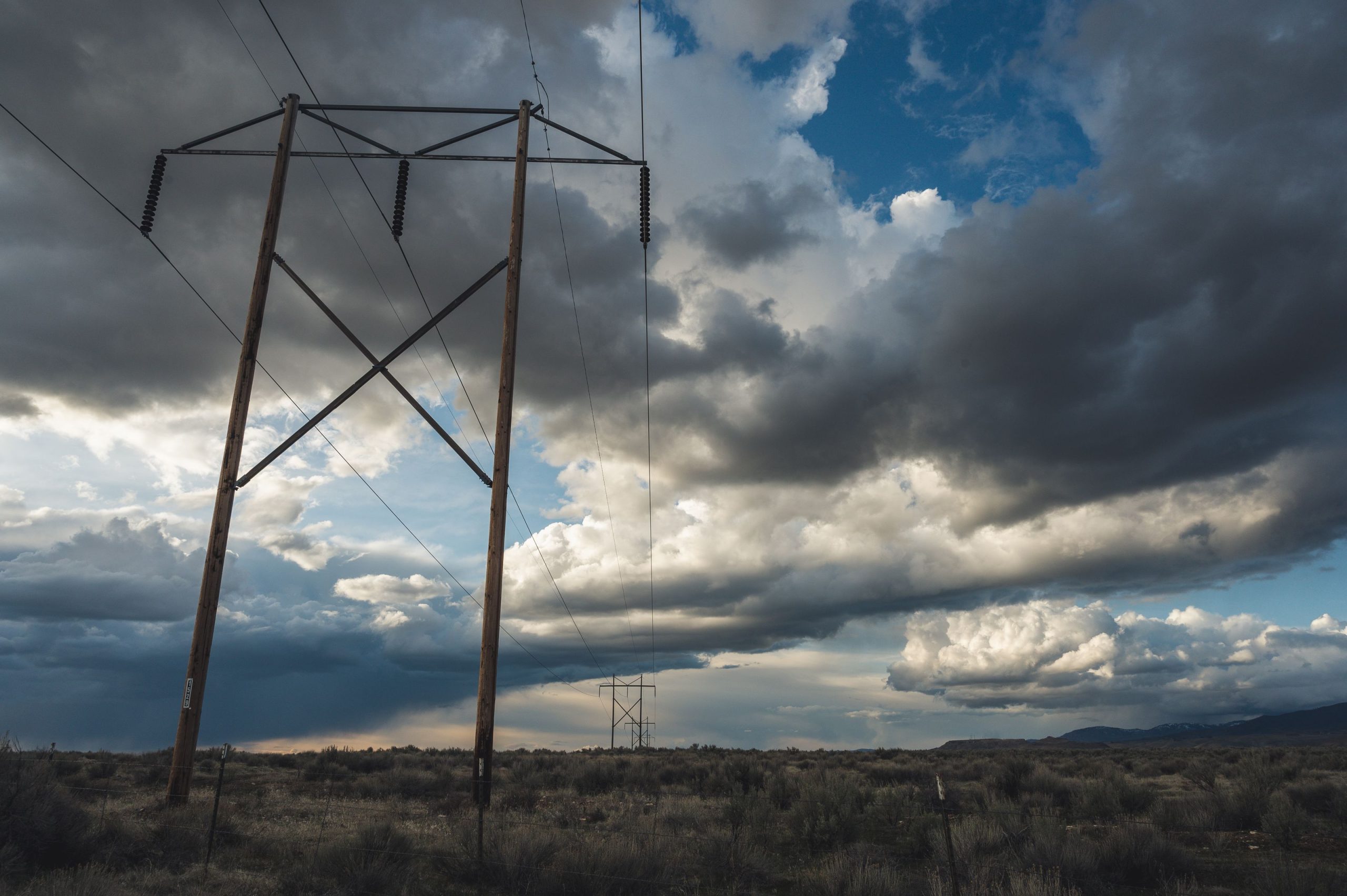 Storm clouds over power transmission lines in an open field
