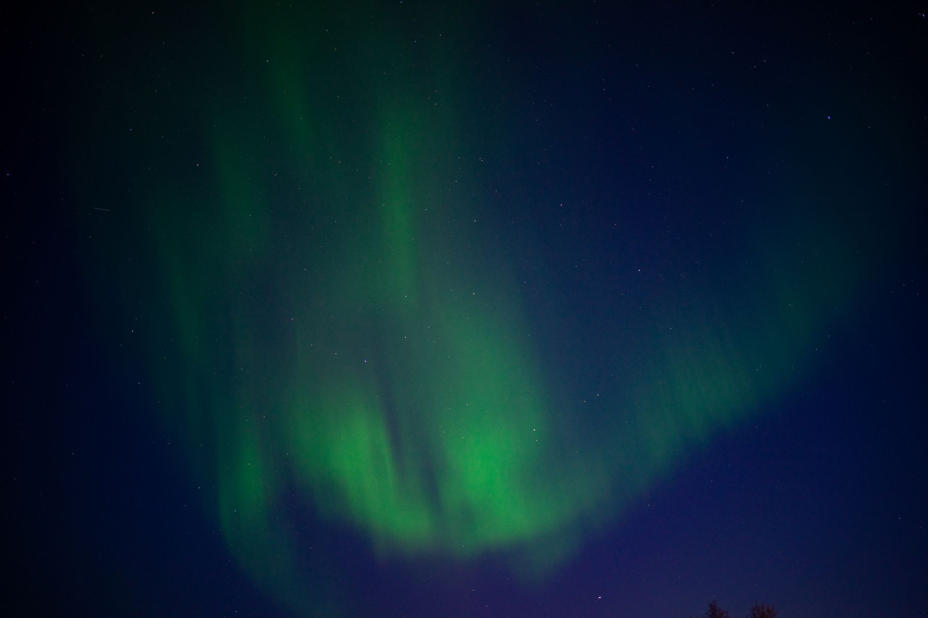 Green aurora borealis over a dark, star-filled night sky