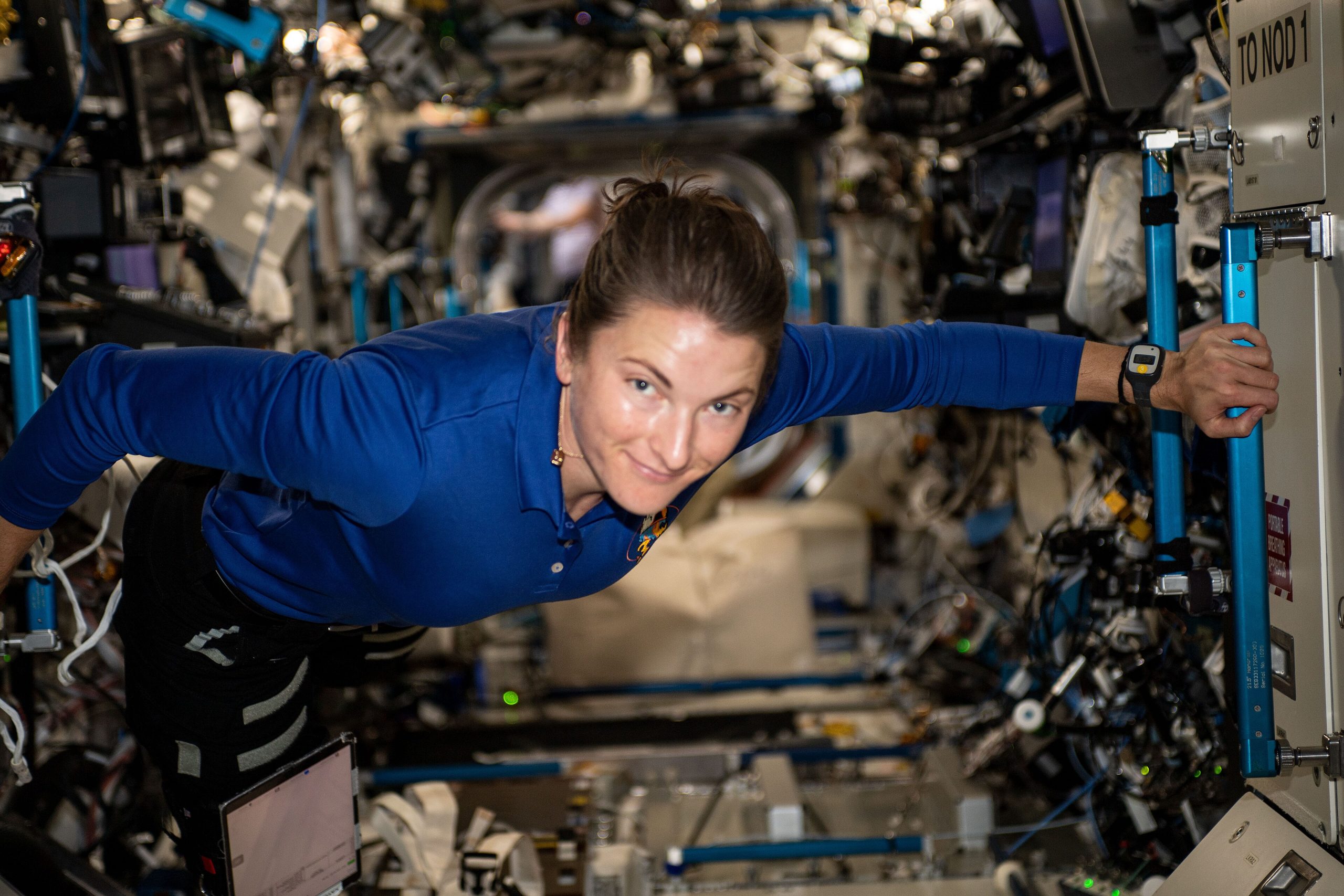 NASA astronaut Kayla Barron floats inside the International Space Station's Destiny laboratory module, holding a handrail, in November 2021.