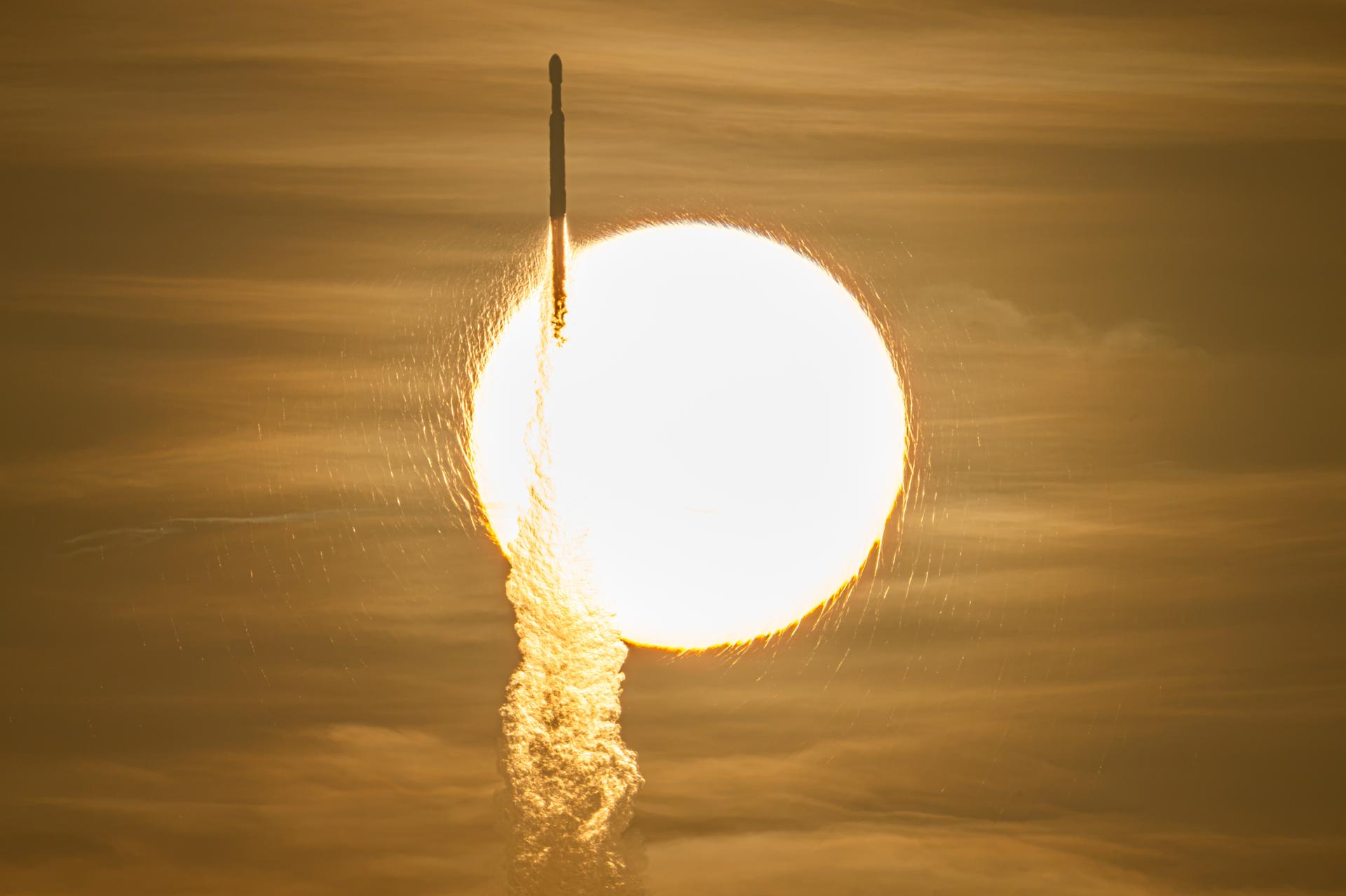 The Nancy Grace Roman Space Telescope launches on a SpaceX Falcon Heavy rocket, silhouetted against the sun