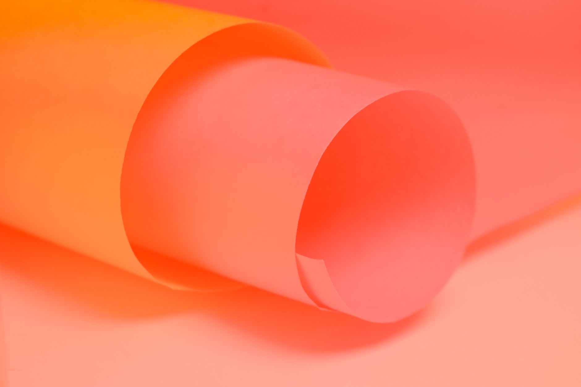 Photo: Close-up of rolled pink and orange paper creating a vibrant abstract background.