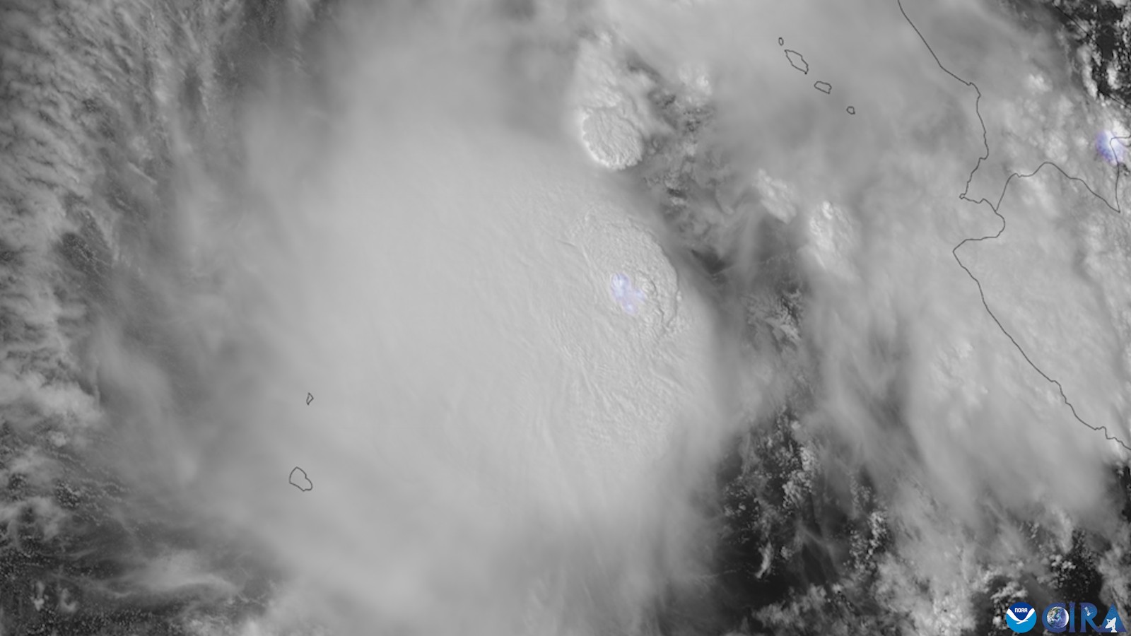 A grayscale satellite image of a large mass of storm clouds over the eastern Pacific just off the west coast of Mexico, with coastline outlines and small islands drawn in dark lines.