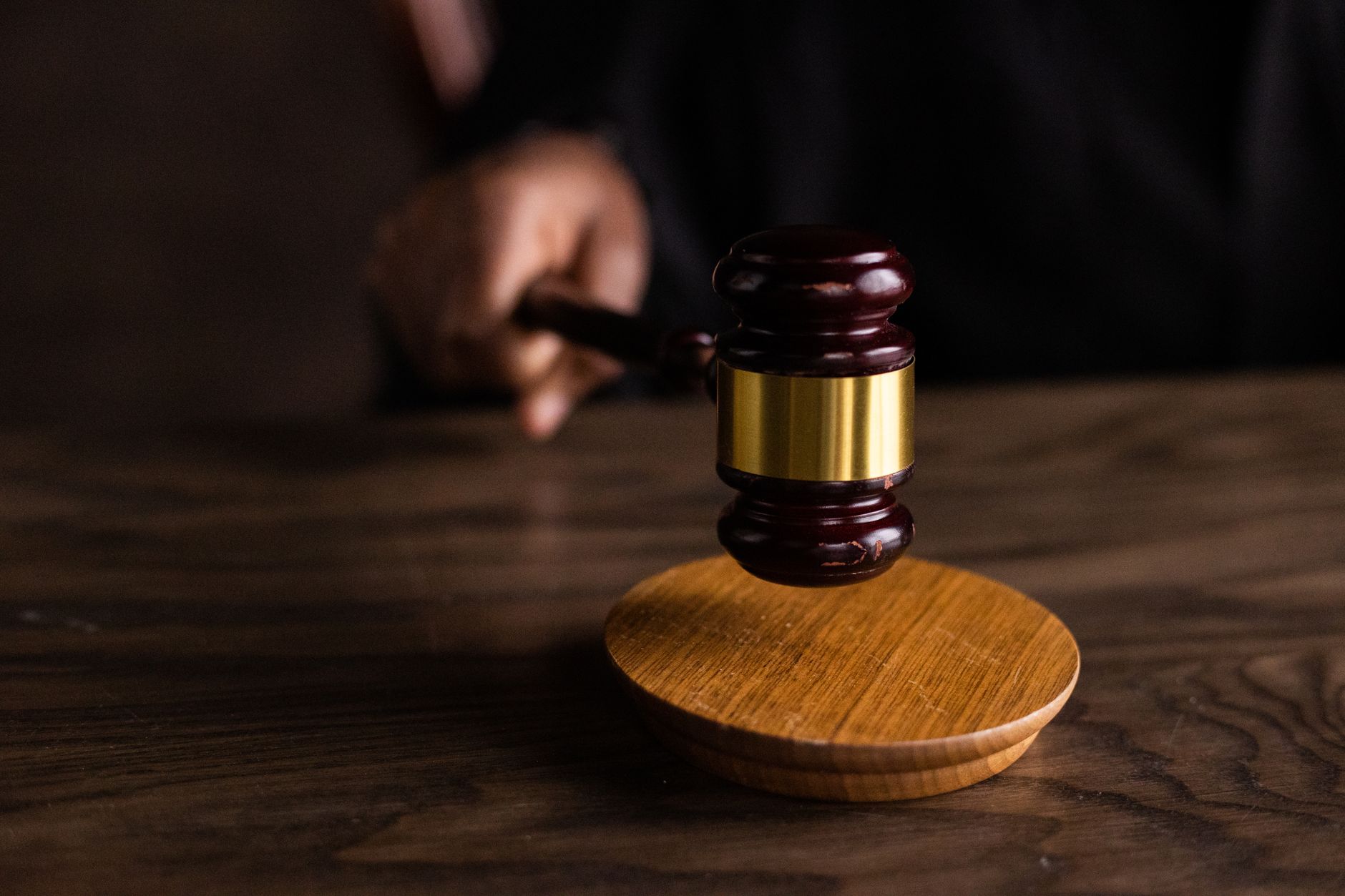 Photo: A gavel striking a sound block, symbolizing justice and legal authority in a courtroom setting.