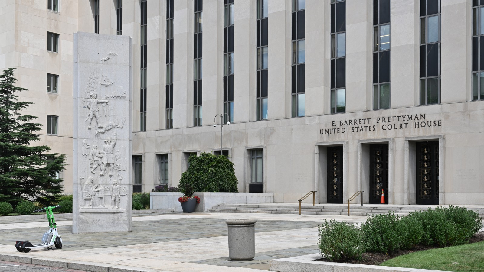 The front of the E. Barrett Prettyman United States Court House in Washington, D.C., a pale stone building with tall narrow windows, a carved stone relief panel and the building's name above its doors.