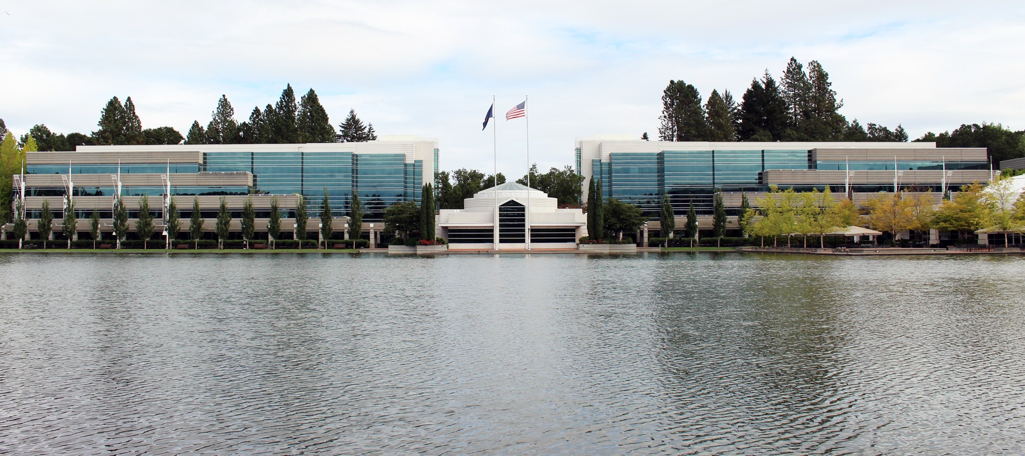 Glass office buildings of Nike's world headquarters in Beaverton, Oregon, seen across a pond, with flags flying in the middle.